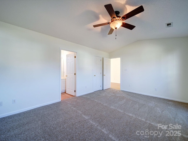 unfurnished bedroom featuring vaulted ceiling, carpet, visible vents, and baseboards