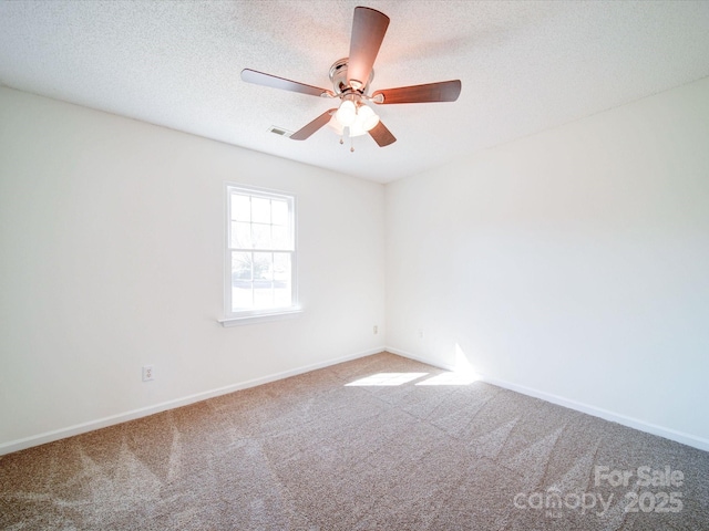 carpeted empty room featuring ceiling fan, visible vents, baseboards, and a textured ceiling