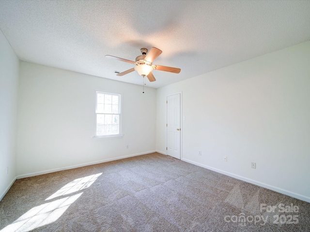 carpeted empty room featuring a textured ceiling, a ceiling fan, and baseboards