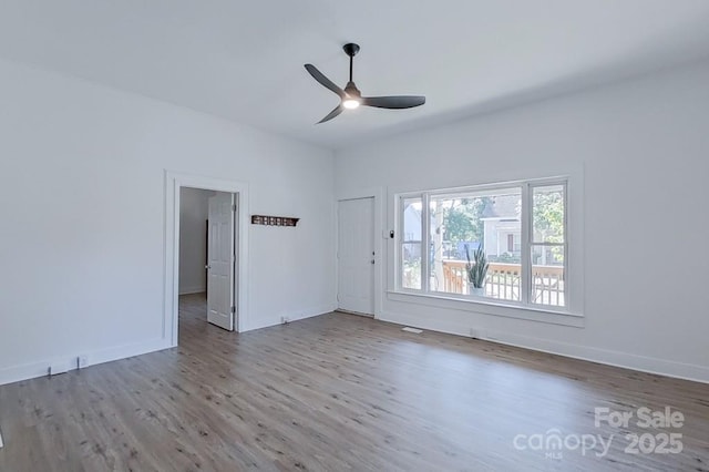 spare room featuring wood finished floors, a ceiling fan, and baseboards