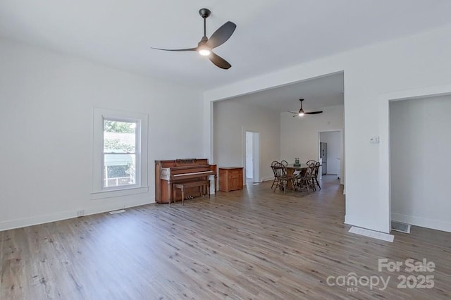 unfurnished room featuring baseboards, ceiling fan, visible vents, and wood finished floors