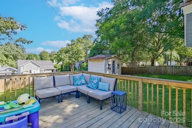 wooden deck featuring outdoor lounge area, an outdoor structure, a lawn, and fence