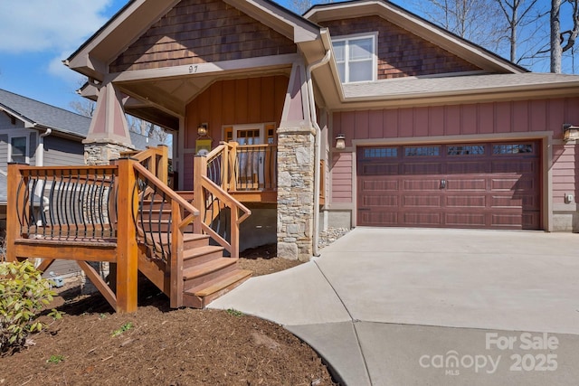 exterior space with concrete driveway, an attached garage, board and batten siding, and stone siding