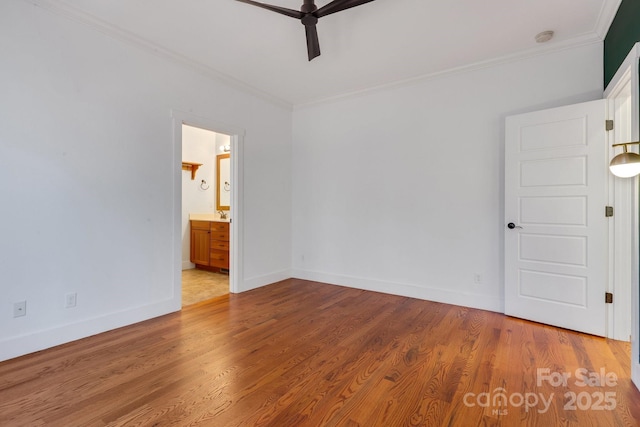 empty room featuring a ceiling fan, wood finished floors, baseboards, and ornamental molding