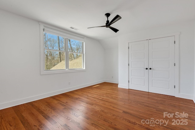 unfurnished bedroom featuring visible vents, baseboards, a closet, and wood finished floors