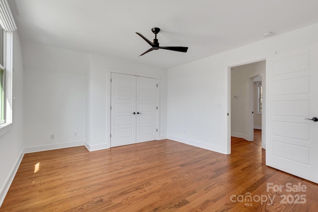 unfurnished bedroom featuring light wood-type flooring, baseboards, a closet, and ceiling fan