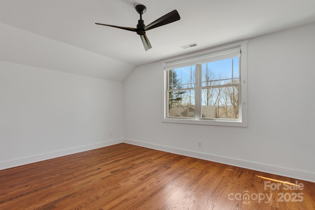 additional living space with wood finished floors, visible vents, baseboards, ceiling fan, and vaulted ceiling