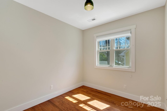 spare room with visible vents, baseboards, and wood finished floors