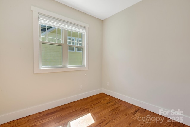 spare room with baseboards and wood finished floors