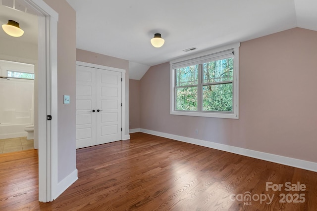 bonus room with lofted ceiling, wood finished floors, visible vents, and baseboards