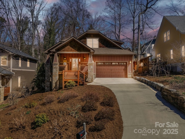 view of front of home with driveway, an attached garage, stairs, stone siding, and board and batten siding