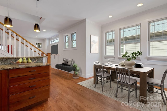 dining area with stairs, crown molding, light wood-type flooring, and a wealth of natural light