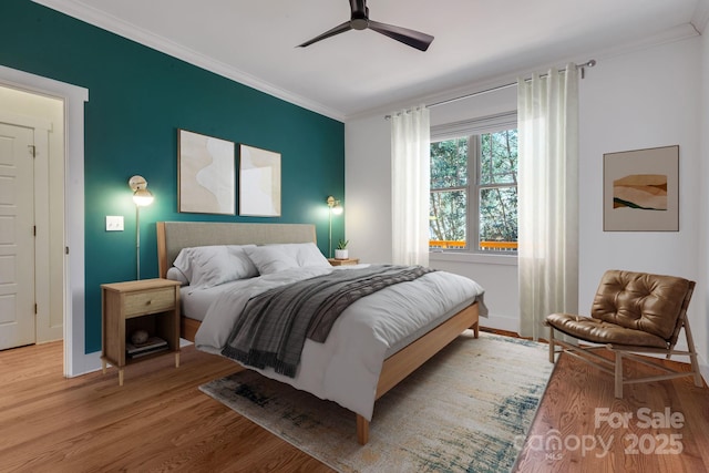 bedroom with ceiling fan, crown molding, baseboards, and wood finished floors