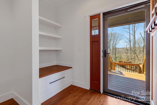 doorway featuring baseboards, dark wood-style floors, and crown molding