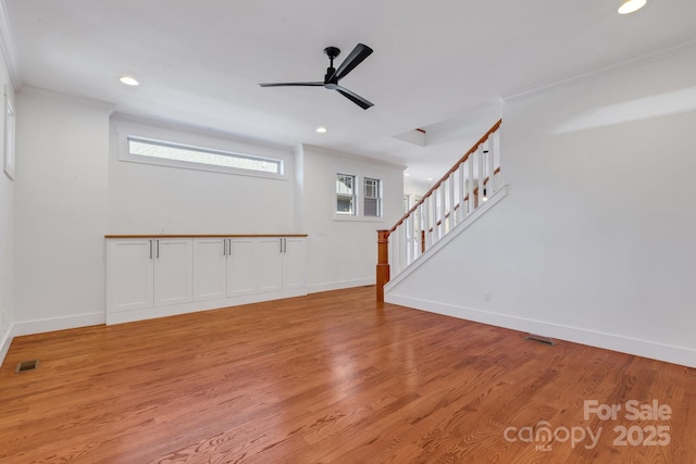 unfurnished living room with visible vents, baseboards, ceiling fan, light wood-type flooring, and ornamental molding