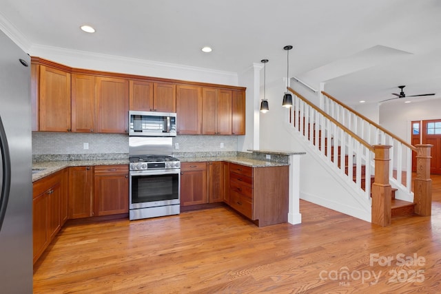 kitchen with light wood finished floors, appliances with stainless steel finishes, crown molding, brown cabinetry, and light stone countertops