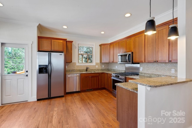 kitchen with brown cabinets, appliances with stainless steel finishes, a peninsula, and a sink