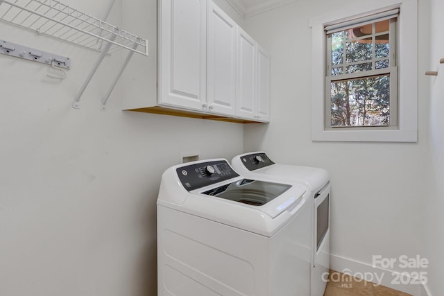 clothes washing area featuring baseboards, cabinet space, and washing machine and clothes dryer