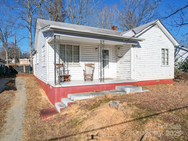 view of front of house featuring driveway, a porch, and a chimney