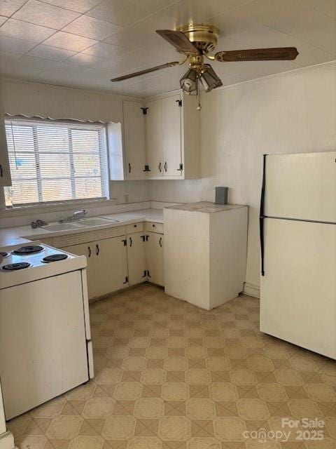 kitchen featuring light floors, light countertops, a ceiling fan, a sink, and white appliances