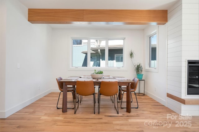 dining room featuring beverage cooler, beamed ceiling, light wood-style flooring, and baseboards