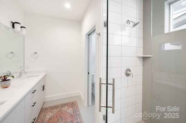 bathroom with toilet, a shower stall, double vanity, and a sink