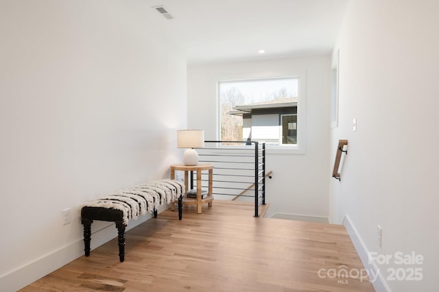 living area featuring baseboards, visible vents, an upstairs landing, and wood finished floors