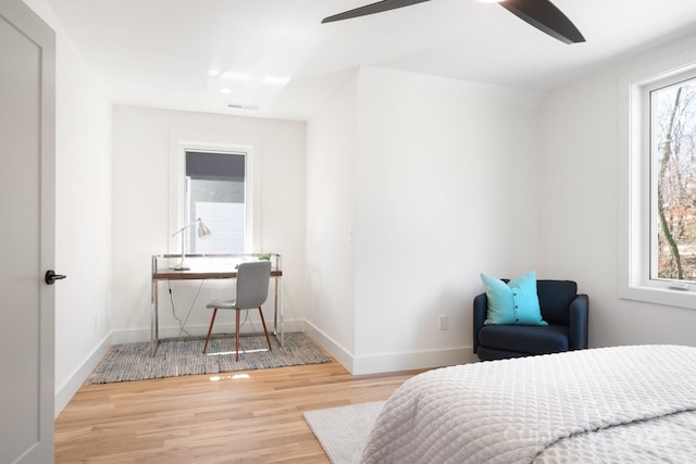 bedroom with a ceiling fan, visible vents, baseboards, and wood finished floors