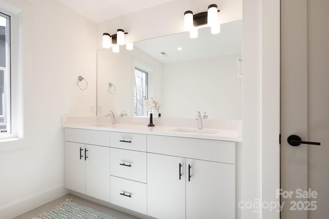 full bath featuring a sink, baseboards, and double vanity