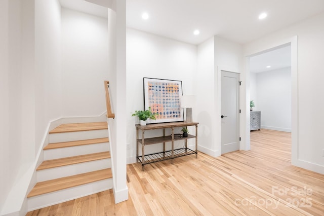 stairs with baseboards, wood finished floors, and recessed lighting