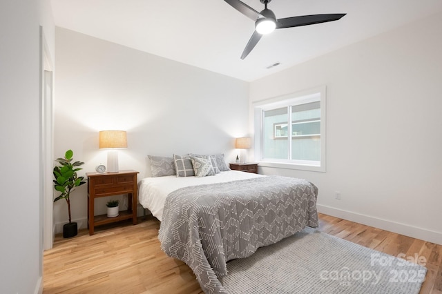 bedroom featuring light wood-style floors, baseboards, visible vents, and ceiling fan