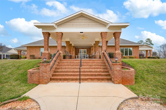 view of front facade featuring a front yard, stairway, covered porch, and brick siding