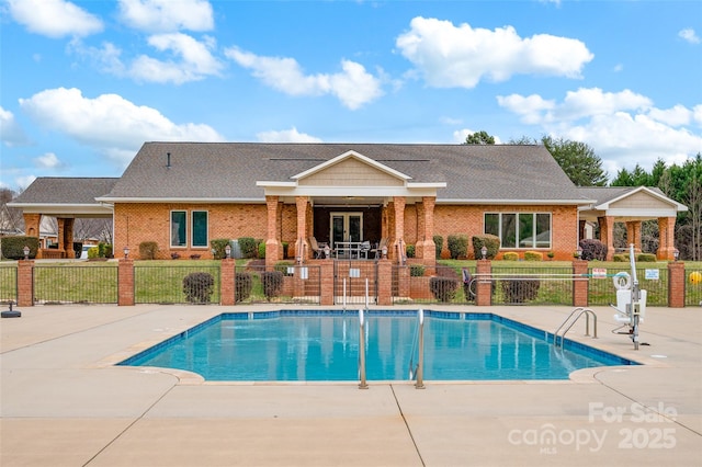 community pool with a patio area and fence