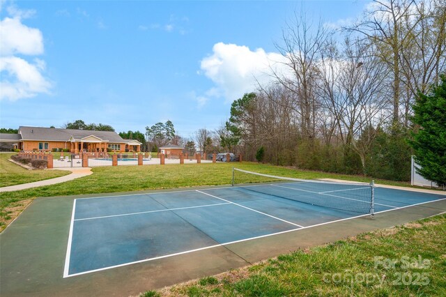 view of tennis court featuring a pool and a lawn