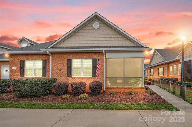 bungalow featuring brick siding and fence