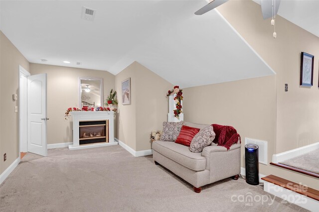 sitting room with visible vents, a glass covered fireplace, carpet, baseboards, and vaulted ceiling