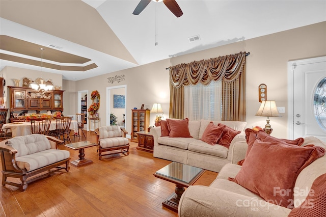 living area featuring a tray ceiling, visible vents, and light wood finished floors