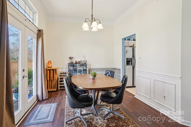 dining area featuring french doors, a wainscoted wall, dark wood finished floors, and ornamental molding