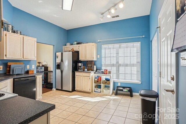 kitchen with light brown cabinets, black dishwasher, dark countertops, stainless steel fridge with ice dispenser, and light tile patterned floors