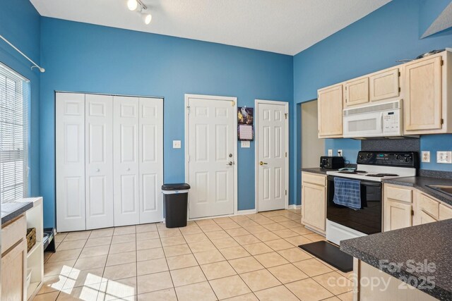 kitchen with light tile patterned floors, white microwave, light brown cabinets, electric stove, and dark countertops