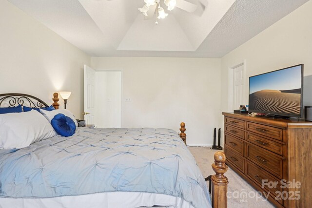 bedroom featuring light carpet, ceiling fan, a textured ceiling, and a tray ceiling