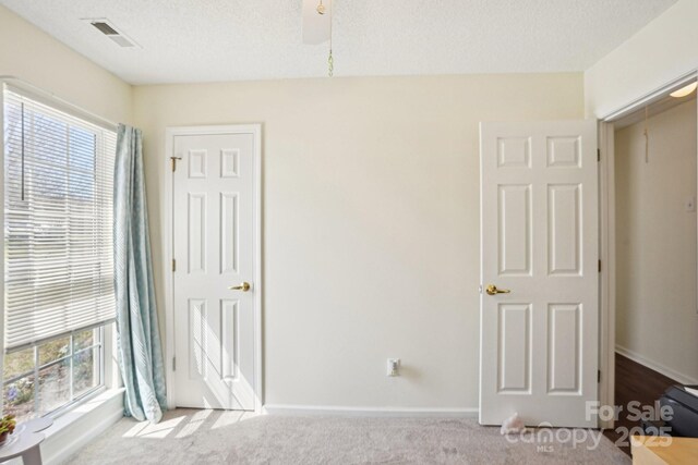 unfurnished bedroom with baseboards, carpet, visible vents, and a textured ceiling