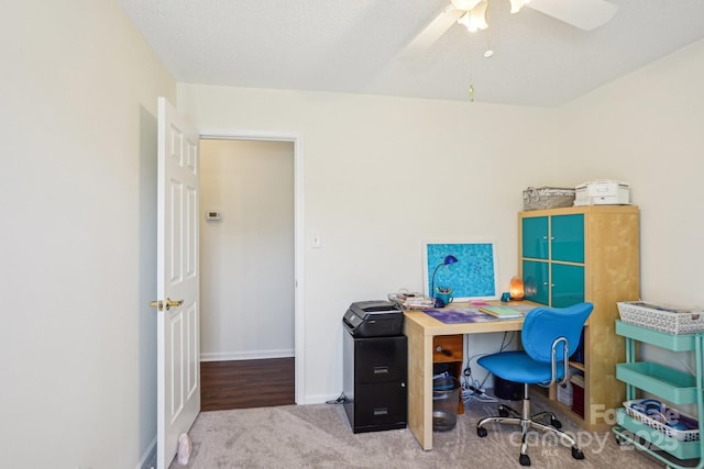 carpeted office space featuring baseboards, a textured ceiling, and a ceiling fan