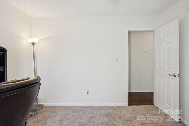 unfurnished office featuring a textured ceiling, baseboards, and carpet