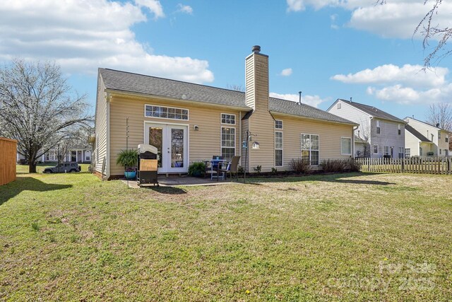 rear view of property featuring a lawn, fence, french doors, and a chimney