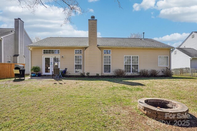 rear view of house featuring a patio, fence, a lawn, and a fire pit