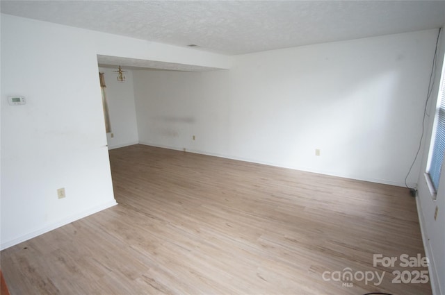 empty room with a textured ceiling and light wood finished floors