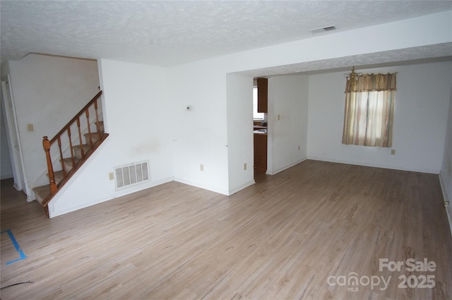 unfurnished living room with stairway, light wood-style flooring, and visible vents