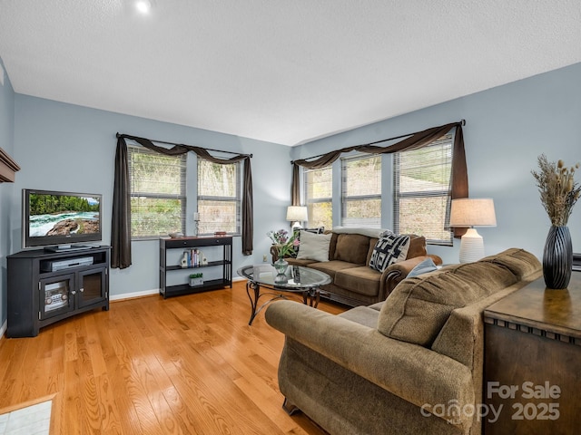 living room with baseboards, plenty of natural light, and light wood-style flooring