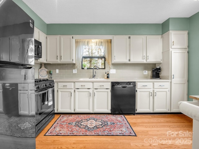 kitchen featuring black appliances, a sink, white cabinetry, light wood-style floors, and light countertops